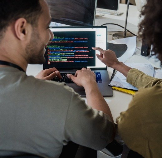 Two developers reviewing code together on a laptop