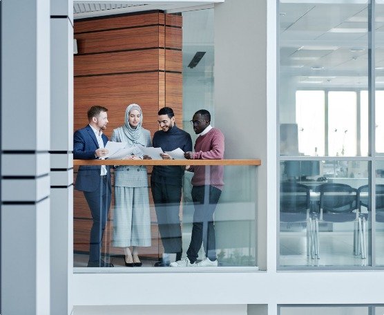 Four colleagues discussing documents in a modern glass office